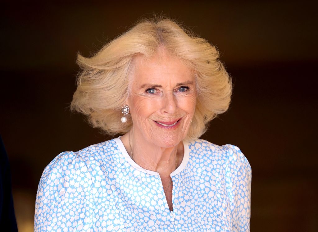 Queen Camilla wearing blue and white dress with pearl earrings