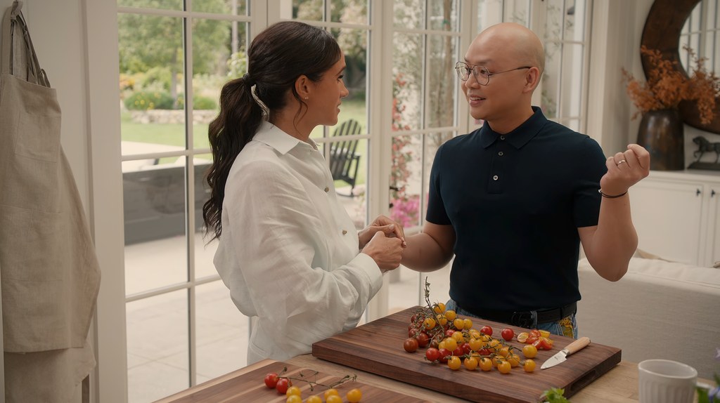 A woman and a man in a kitchen cutting tomatoes