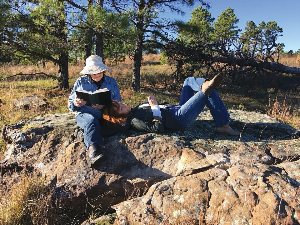 Reba McEntire sits with her head resting on her mom's lap as her mom reads a book