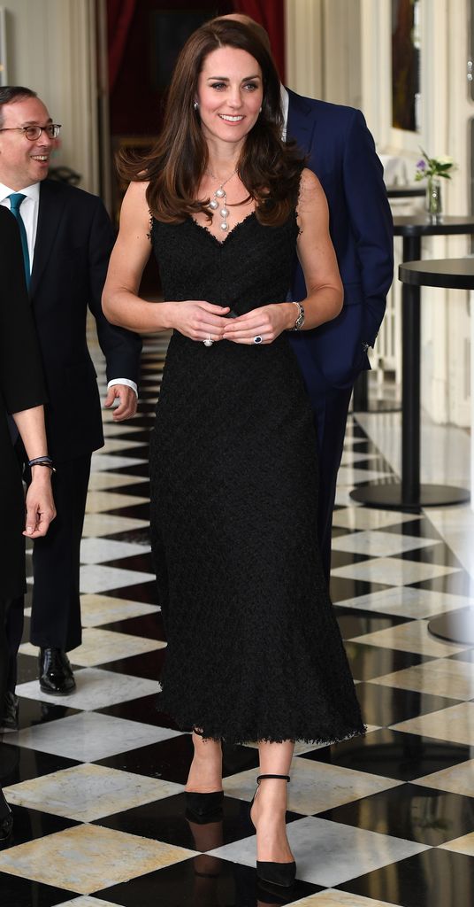 Catherine walking through hall in black dress