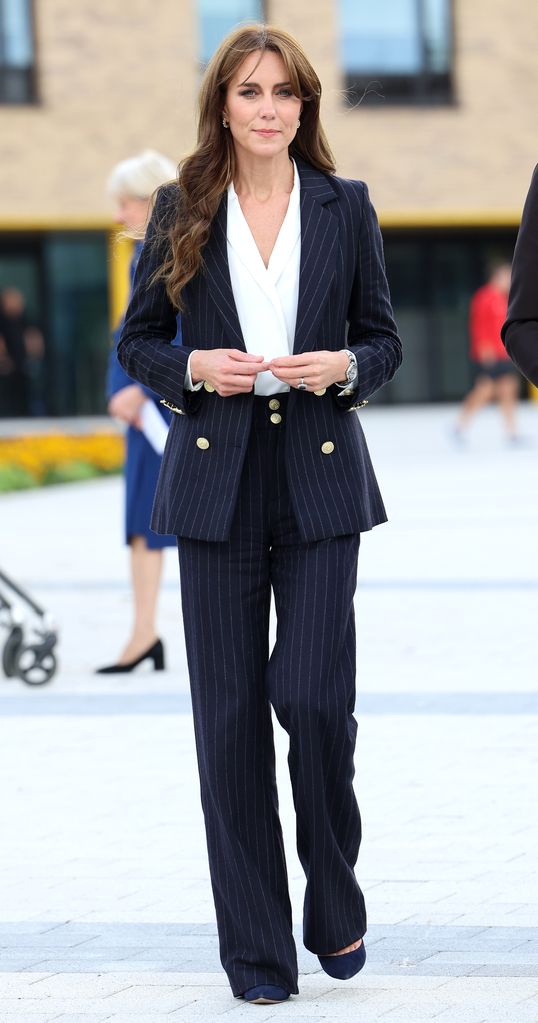 Kate in a pinstripe navy suit with a white top