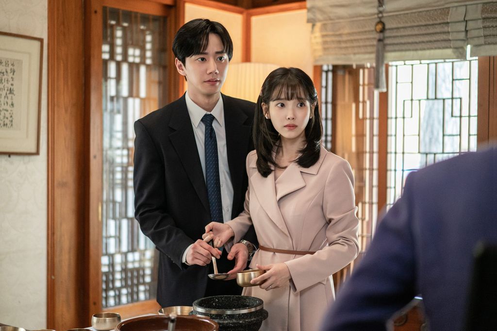 young man in suit with young woman in pink coat in house