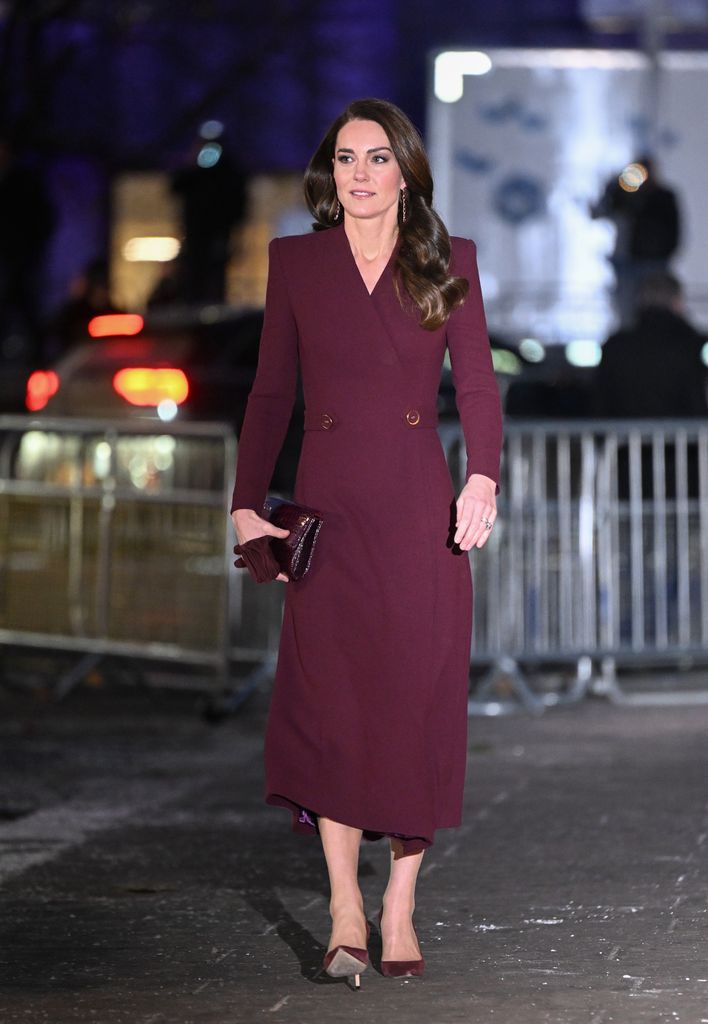 Kate em um vestido de casaco cor de vinho e salto alto