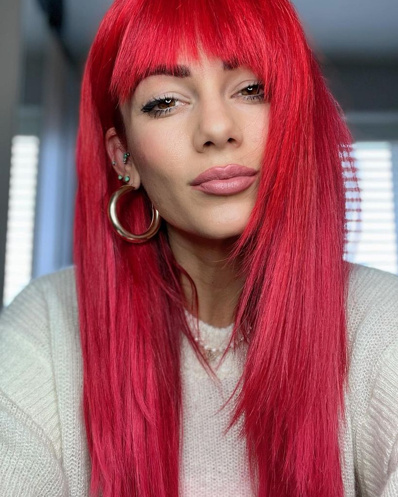 Dianne Buswell with straight red hair and fringe and pink highlights