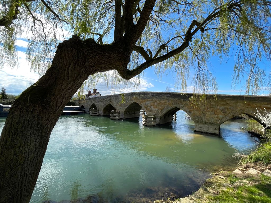 A medieval stone bridge over the River Thames in Oxfordshire, UK, on a bright spring morning. 