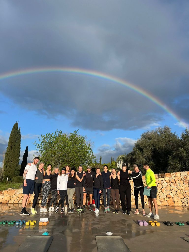 group of women standing underneath a rainbow in activewear