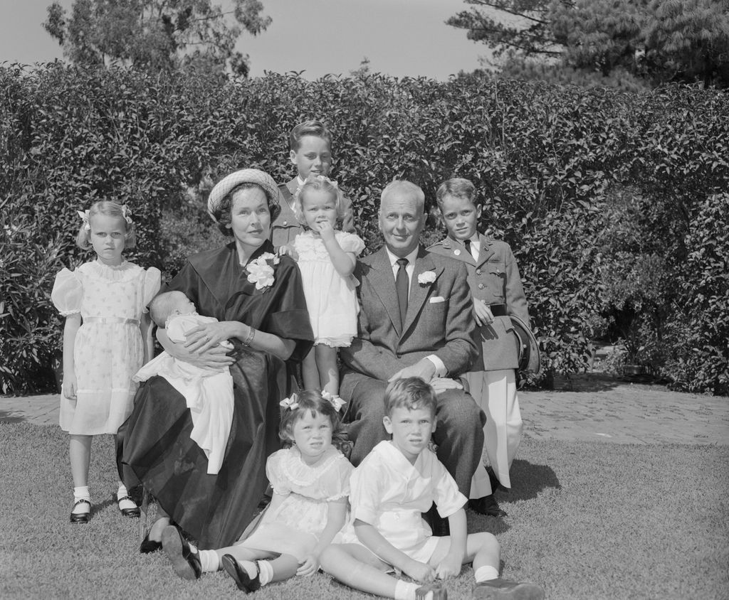 The growing family of actress Maureen O'Sullivan and director John Farrow pose for portrait following christening of their seventh child at Church of the Good Shepherd here. Seated in front are Prudence, 3; and John Jr., 4. Second row: Maria, 6; Mrs. Farrow olding month old Thersa; Stephanie, 2; John Farrow; and Patrick, 8. Peeping over the rear is Stanley, 12