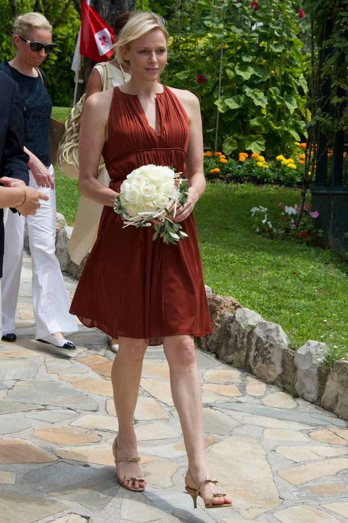 Princess Charlene in brown dress holding flowers