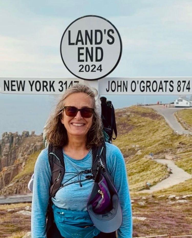 Woman in a blue top standing in front of the land's end sign in Cornwall 