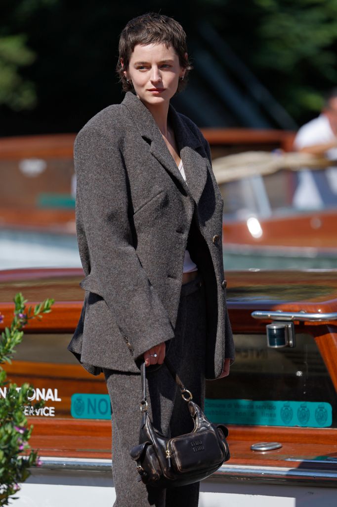 Emma Corrin arrives at Hotel Excelsior during the 82nd Venice International Film Festival in grey suit