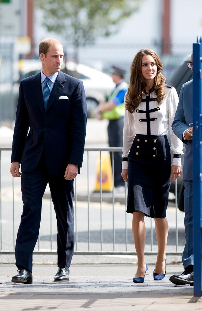 Kate in a pencil skirt and white blouse beside william