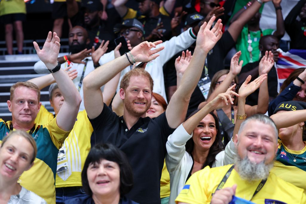 Meghan Markle and Prince Harry waving their hands in the air