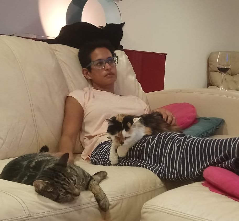 naga munchetty lying on her sofa in pyjamas with her cats 