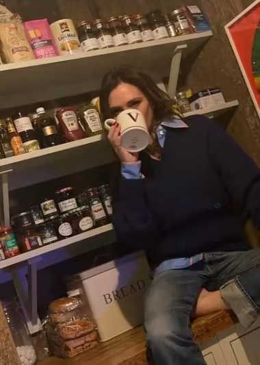 victorial beckham sips from a mug surrounded by shelves full of jars in a pantry