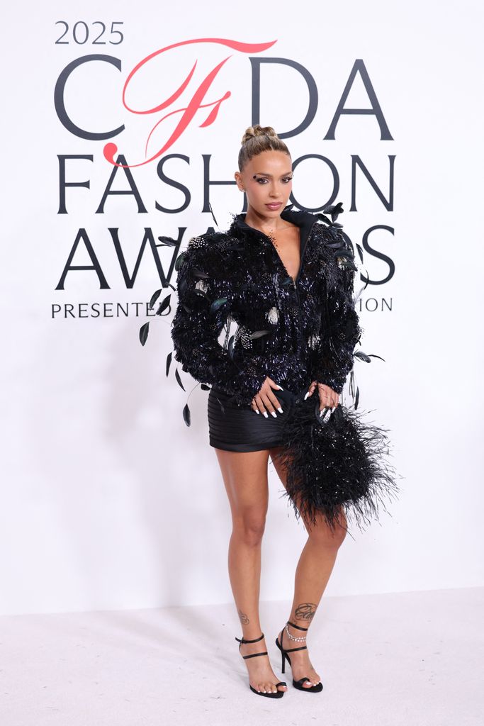 Bad Gyal attends the CFDA Fashion Awards wearing a black sequin jacket,  black mini skirt, black high heels and a fluffy black bag