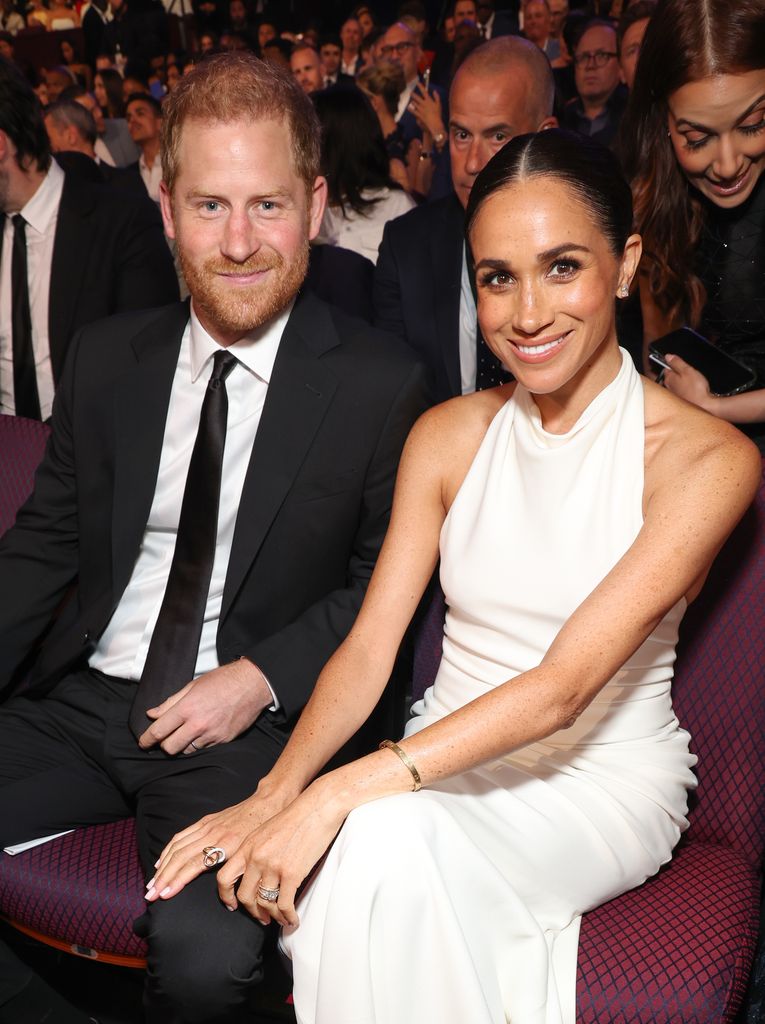Prince Harry in a suit sat next to Meghan Markle in a white long dress