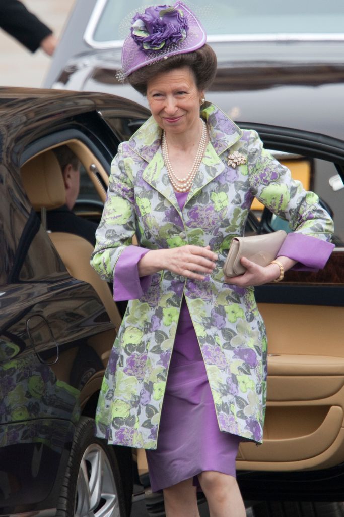 Princess Anne in a purple and green dress getting out of a car