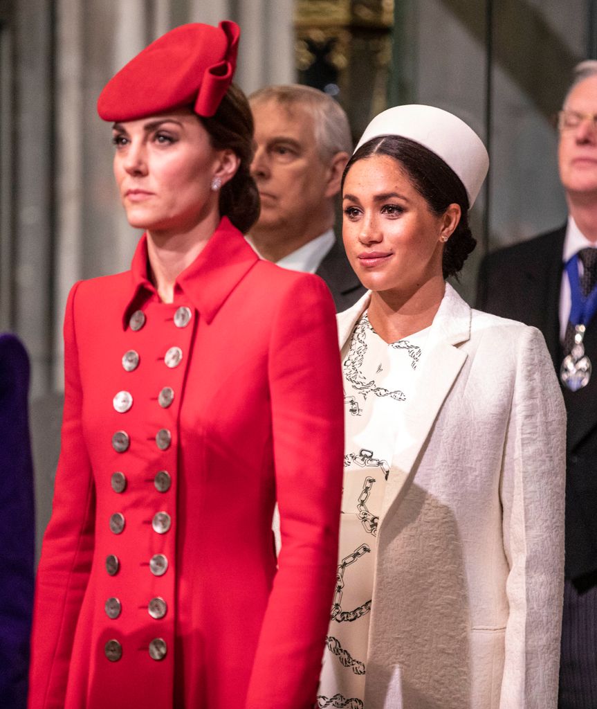 Kate Middleton in a red dress with Meghan Markle behind her