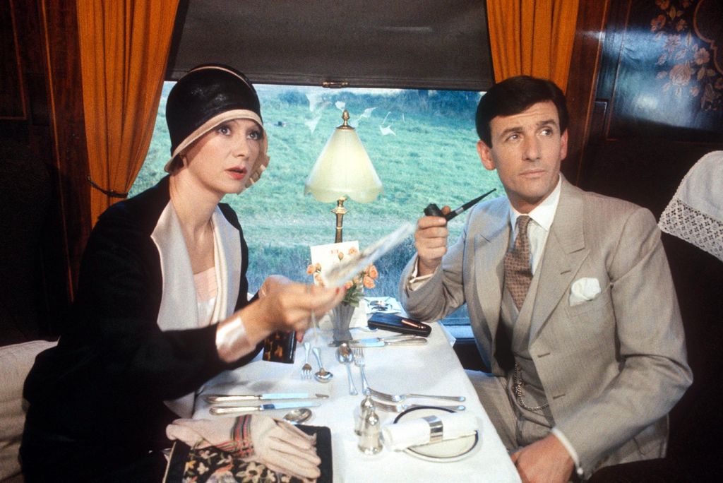 woman and man in period dress sitting on train