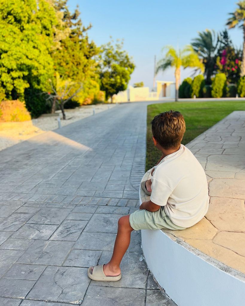 young boy sitting on stone wall 