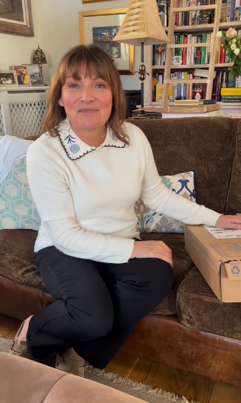 Lorraine Kelly smiling for the camera while sitting on a brown sofa in her living room at home