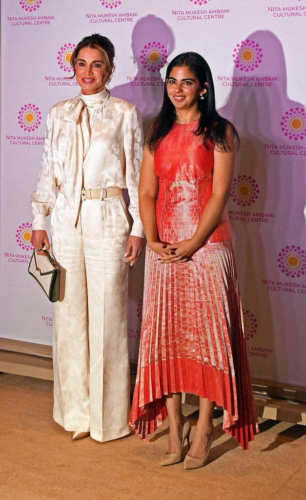 Rania en blouse et pantalon blancs et Isha Ambani en robe corail ont posé pour une photo 