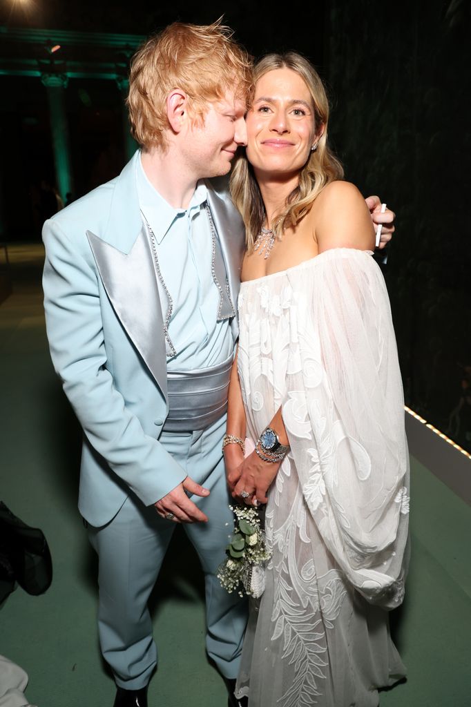 Ed Sheeran in a pastel blue satin suit cosying up to Cherry Seaborn in a white off shoulder dress