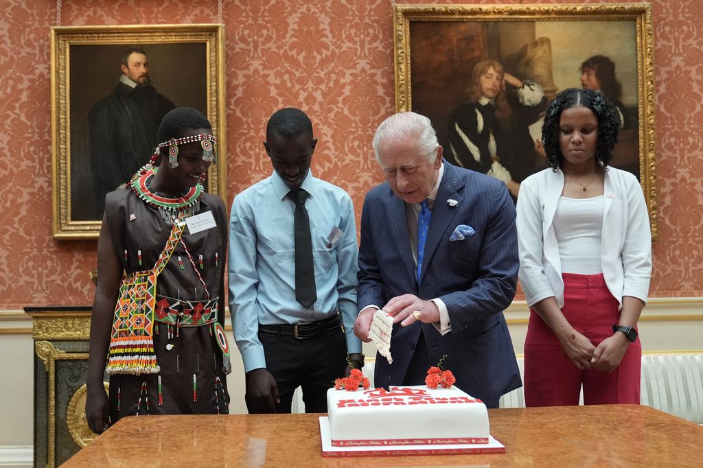 King Charles with three people slicing into a cake