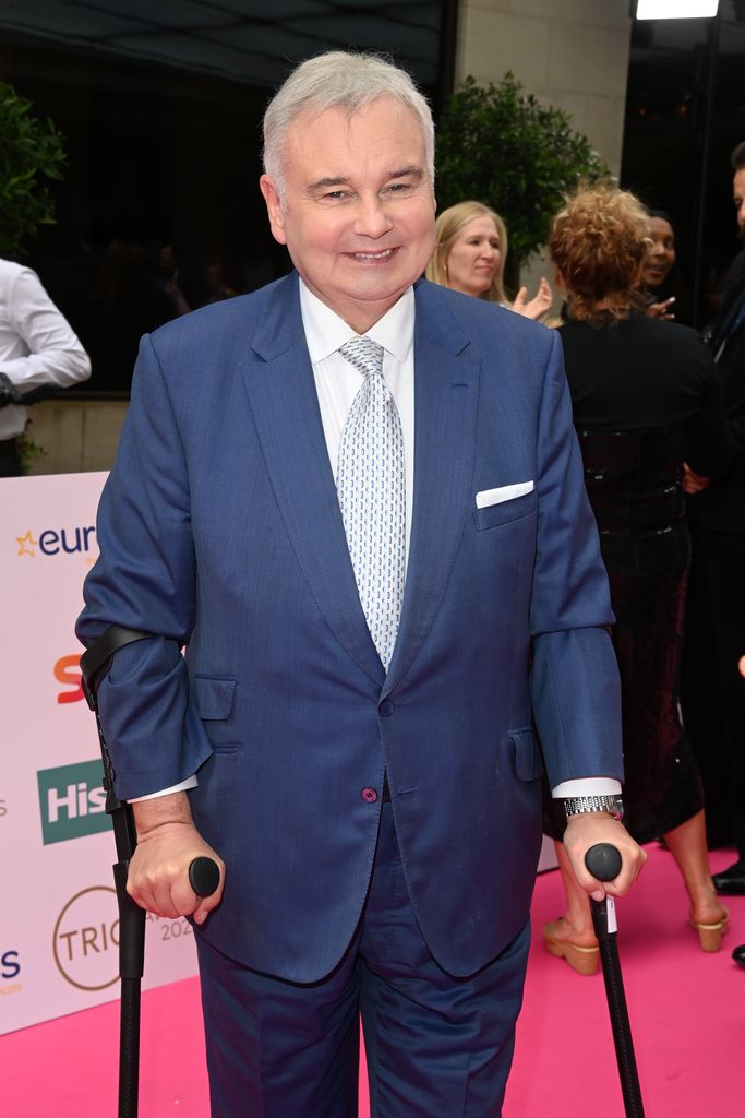 Eamonn Holmes in blue suit with crutches
