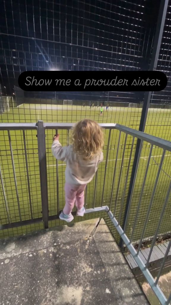 Helen Skelton's daughter Elsie standing on railings looking at a football pitch