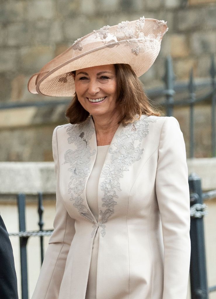 Carole Middleton em vestido e chapéu esbranquiçado