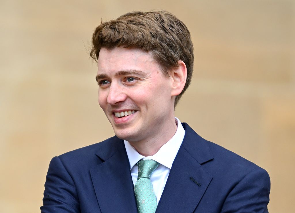 Euan Blair dans un costume bleu, les bras croisés