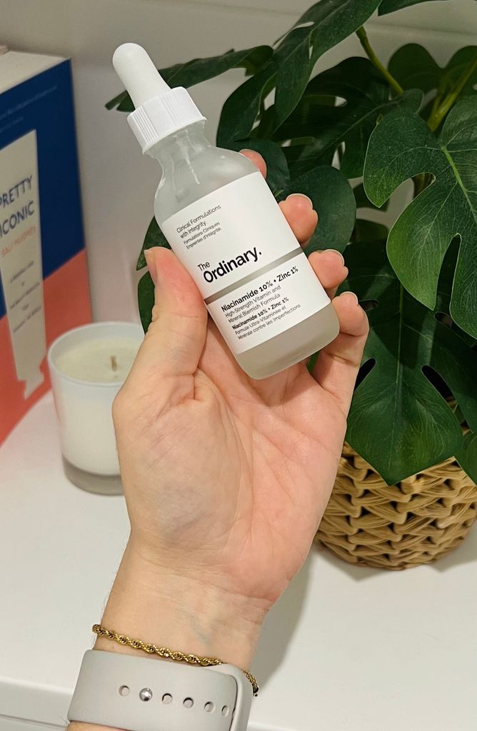 Hand holding up a bottle of The Ordinary Niacinamide serum