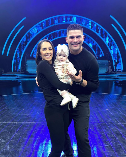 A photo of Janette Manrara and Aljaz Skorjanec on stage with their daughter Lyra Rose