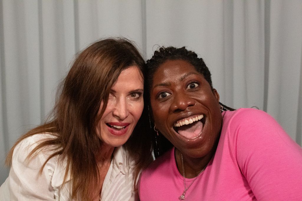 two woman smiling widely and happily in a podcast studio