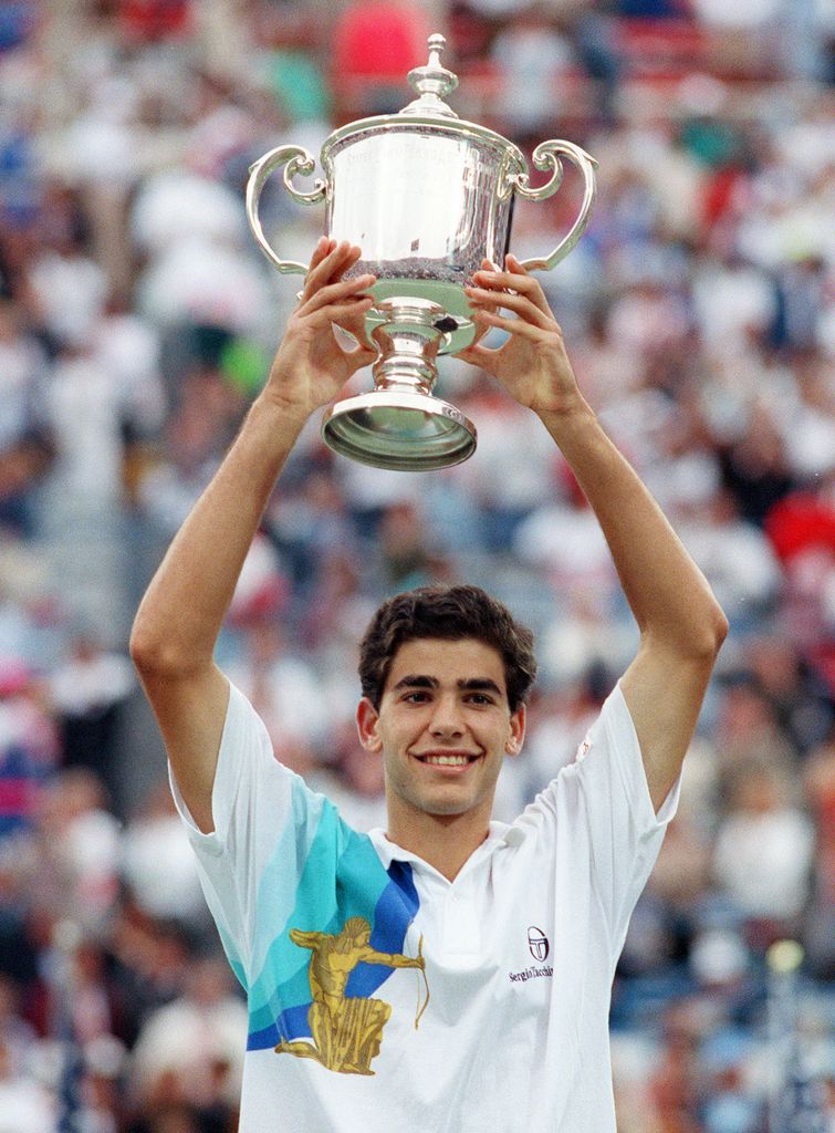 tennis player holding trophy above head 