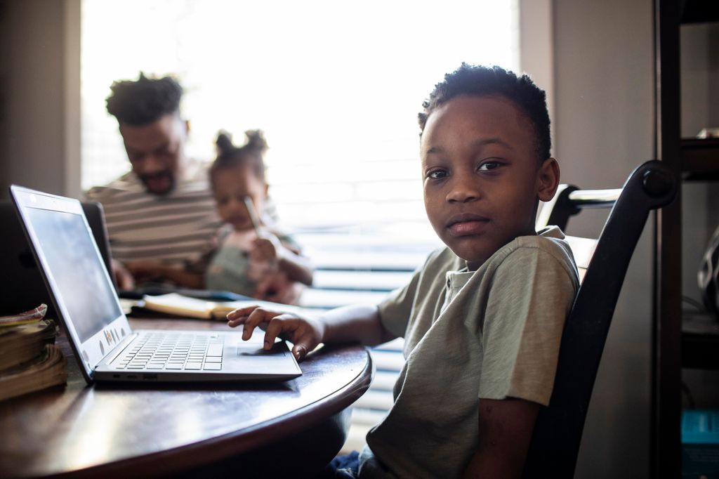 Young boy e-learning at home with family 