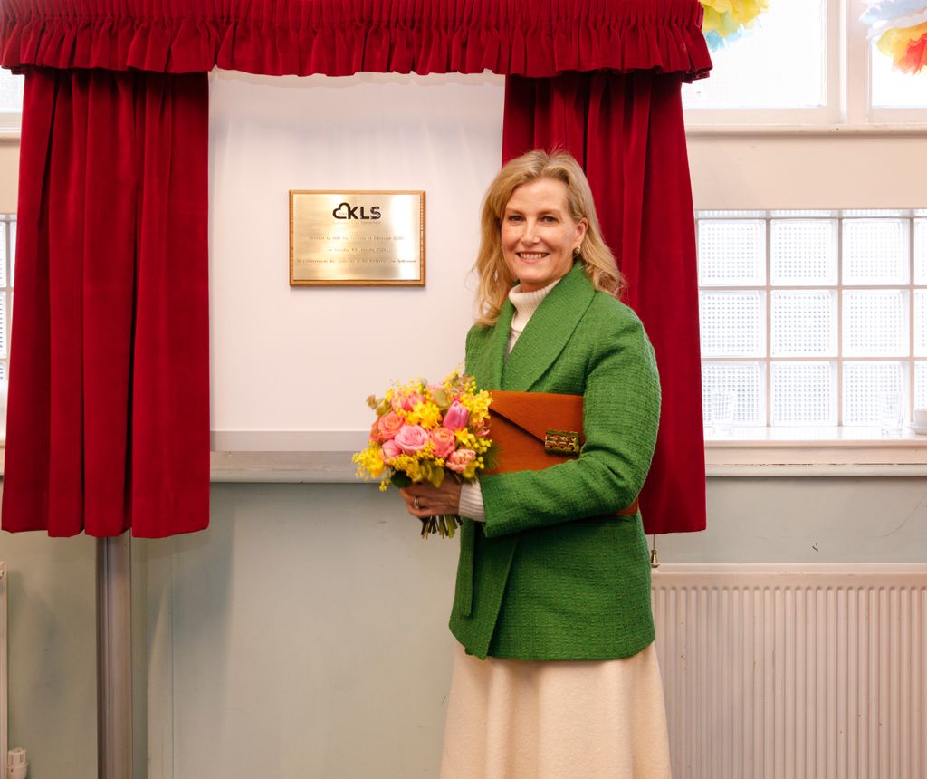 Duchess Sophie standing by plaque holding flowers