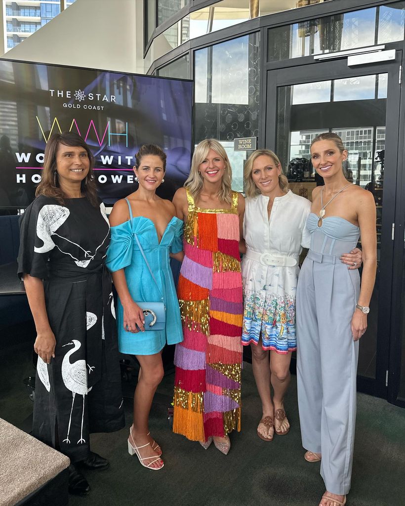 Zara Tindall wears a white mini dress with a seascape print as she stands with a group of glamorous women