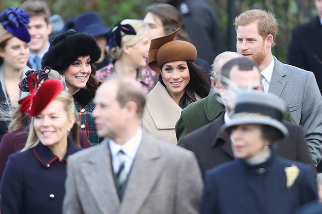the camera is focused on kate meghan and harrys smiling faces as they walk outside among other members of the royal family