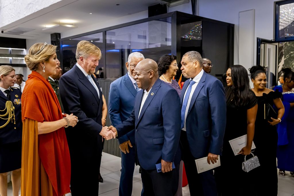 Queen Maxima in orange caped gown meeting group of people