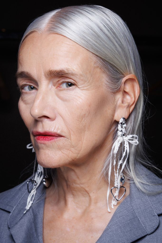Red lipstick on an older model with white hair backstage at Marco Rambaldi
