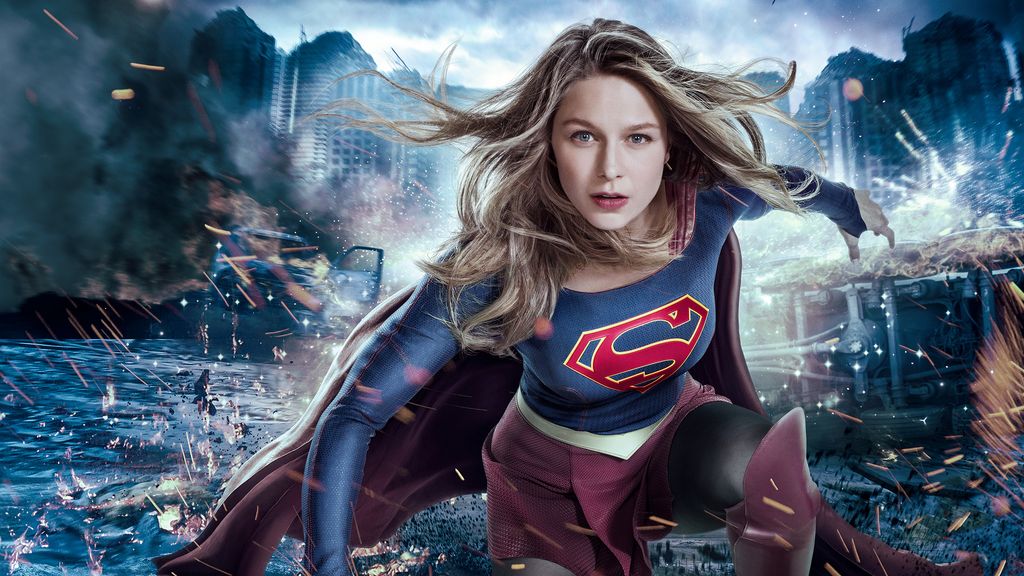 woman in superhero costume in front of city with smoke and fire