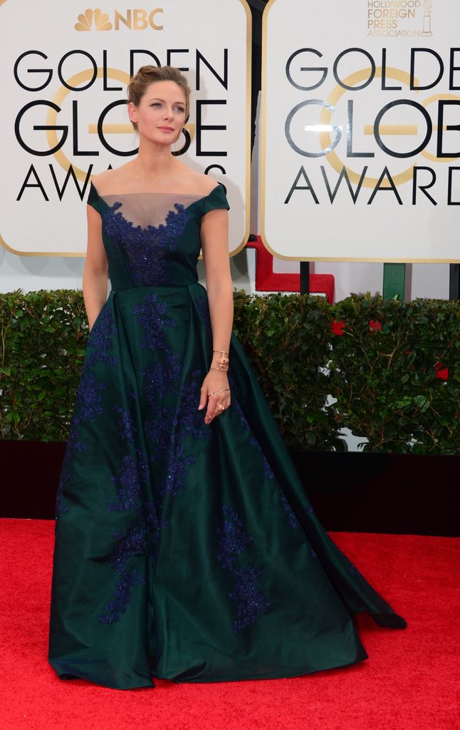 Rebecca wears an emerald gown with floral appliqué and sheer neckline at the Golden Globes, exuding classic elegance.