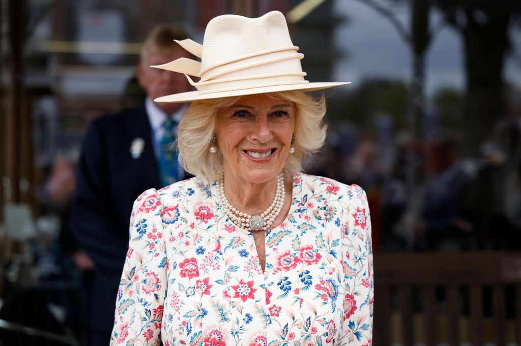 Queen Camilla smiles in floral dress and hat