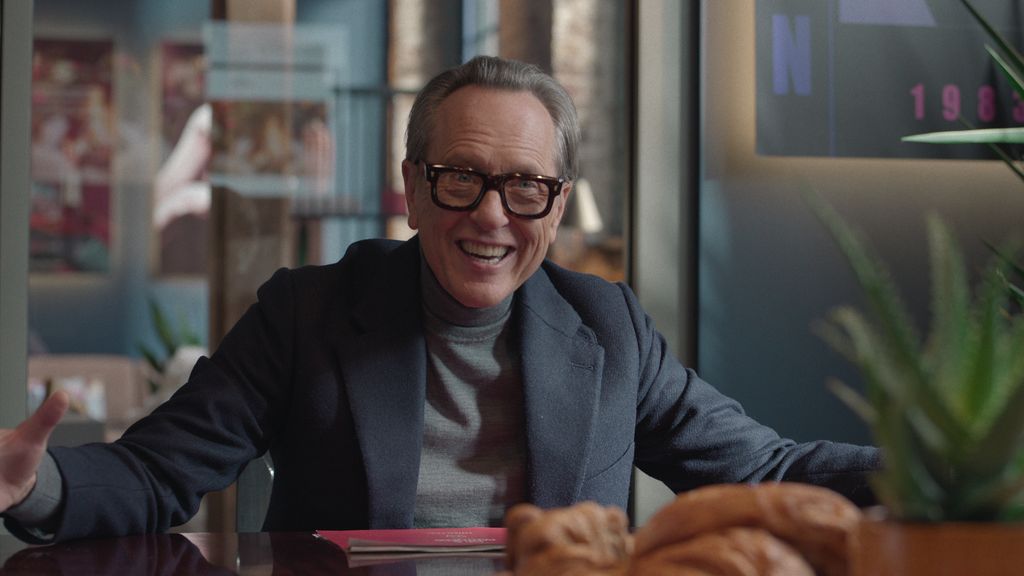 man in grey suit and glasses smiling