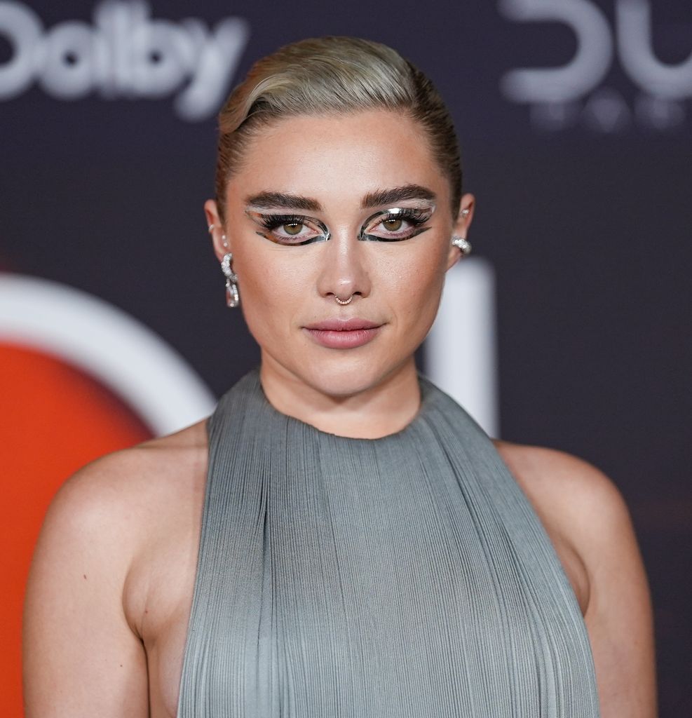 Florence Pugh with silver reflective eye stickers in backless grey dress 
