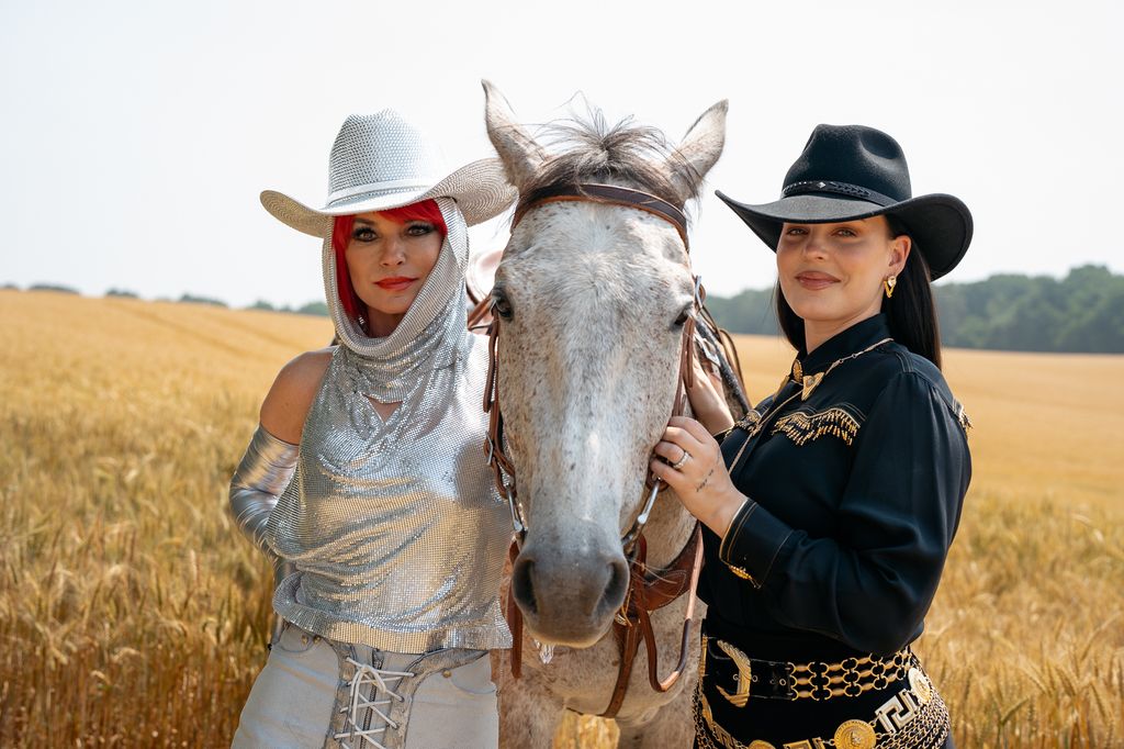 Shania and Anne-Marie stand next to a white horse