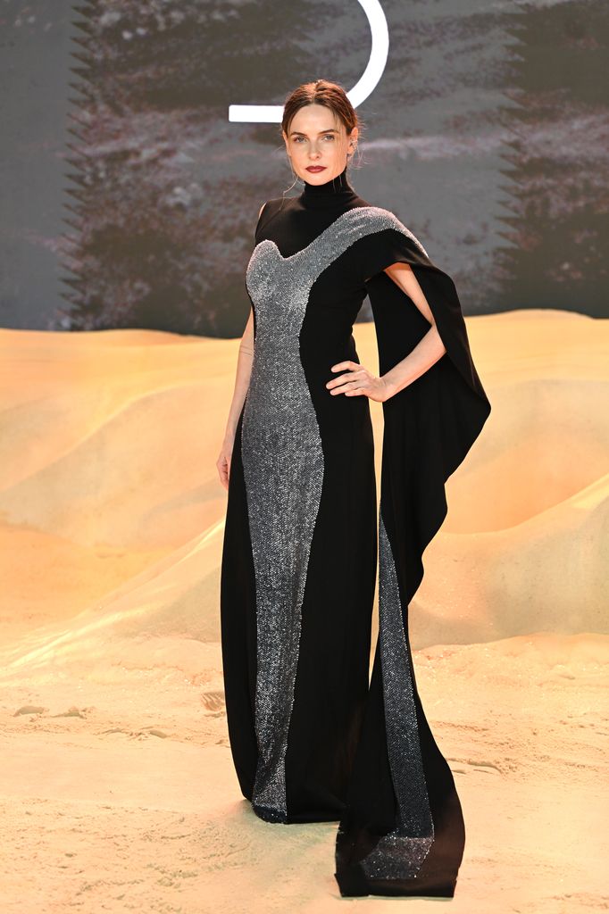 In a black gown with shimmering silver panels and cape sleeves, Rebecca epitomizes futuristic drama at a Dune premiere.