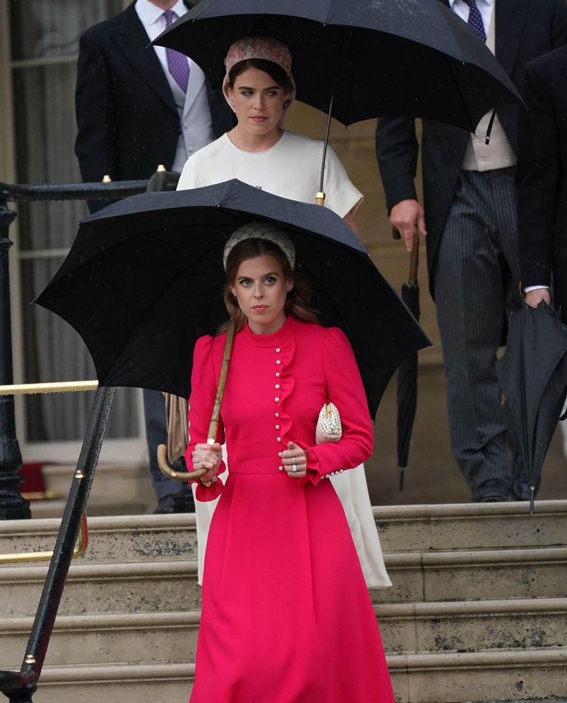 Princess Beatrice and Princess Eugenie wearing statement headbands under umbrella